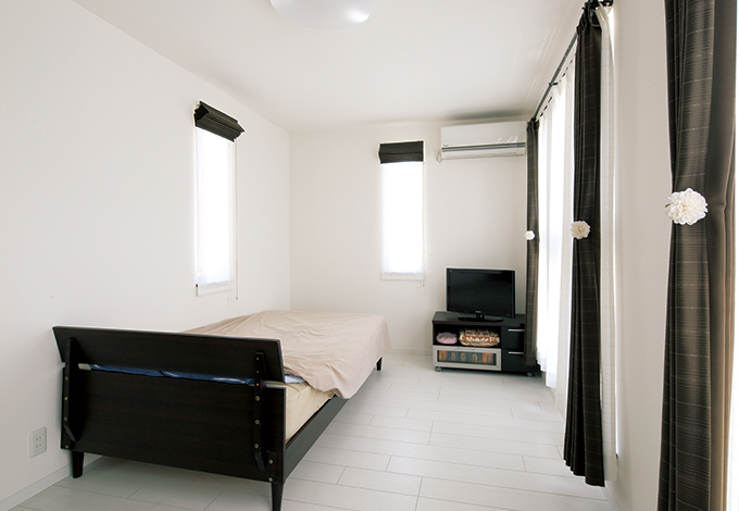 L字型の寝室も、シンプル&シックに まとめた。大きなスリット窓を組み合わせ て、プライバシーに配慮しながらも、充分 な明るさと風通しの良さを実現