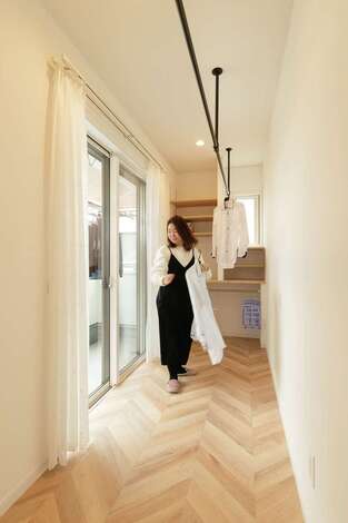 2階の寝室からアクセスできる3畳のサンルーム。部屋干しポールはアイアン、床はヘリンボーンのフロアタイル。夜干して朝には乾く。天気のいい休日はバルコニーで干すことも