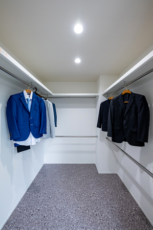 スーツが整然と吊るされたウォークインクローゼット。広々とした空間で、衣類がしっかりと収納できる設計。