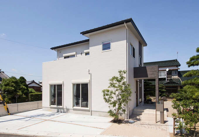 シンプルなホワイトの外観。シンボルツリーが家族の成長を見守る