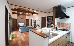 オープンスタイルのキッチンからリビングを望む。高い天井と梁が印象的で、広々とした空間を提供