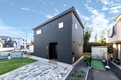 塗り壁調の黒い外壁とベージュの木目がソリッドな重厚感を与える