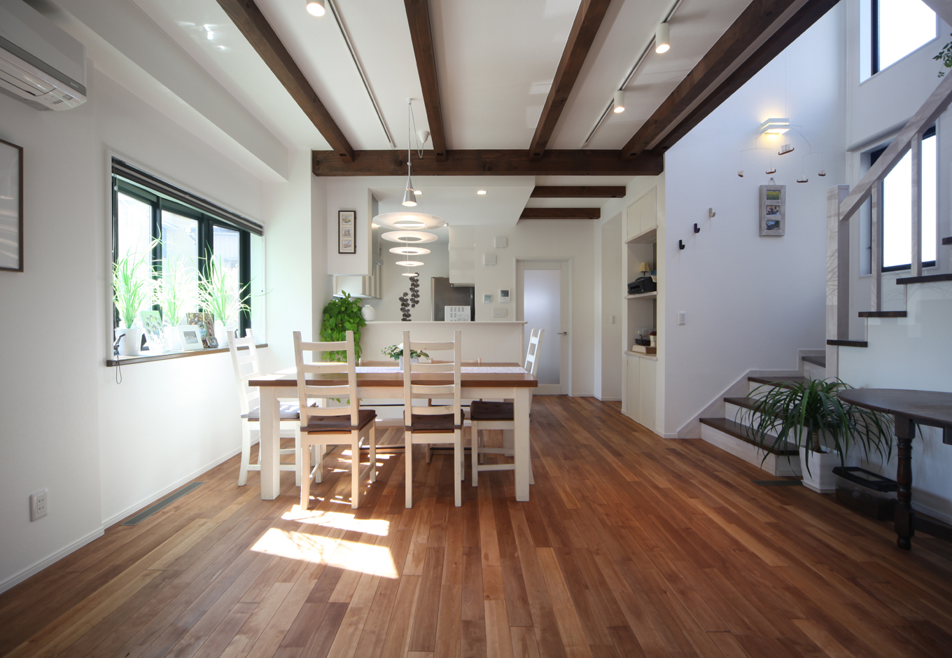 ソーラーホーム/OMソーラーの家【デザイン住宅、子育て、省エネ】ダークブラウンの無垢の床に、白い壁や北欧テイストの家具が良く映える。天井に走らせた梁が空間に奥行きを出し、LDKの中央に設けた吹き抜けの階段と共に開放感を増している
