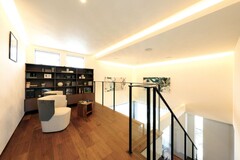 照明が印象的なフリースペース。階段前には本棚が配され、くつろぎの空間が広がっています。多目的に利用可能で、家庭内での様々なアクティビティに対応できます。