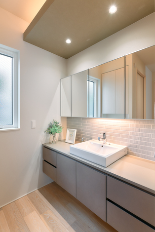 シンプルでモダンなデザインの洗面スペース。広さを感じさせる大きな鏡と、使い勝手の良いカウンターが特徴的で、清潔感が漂っている。