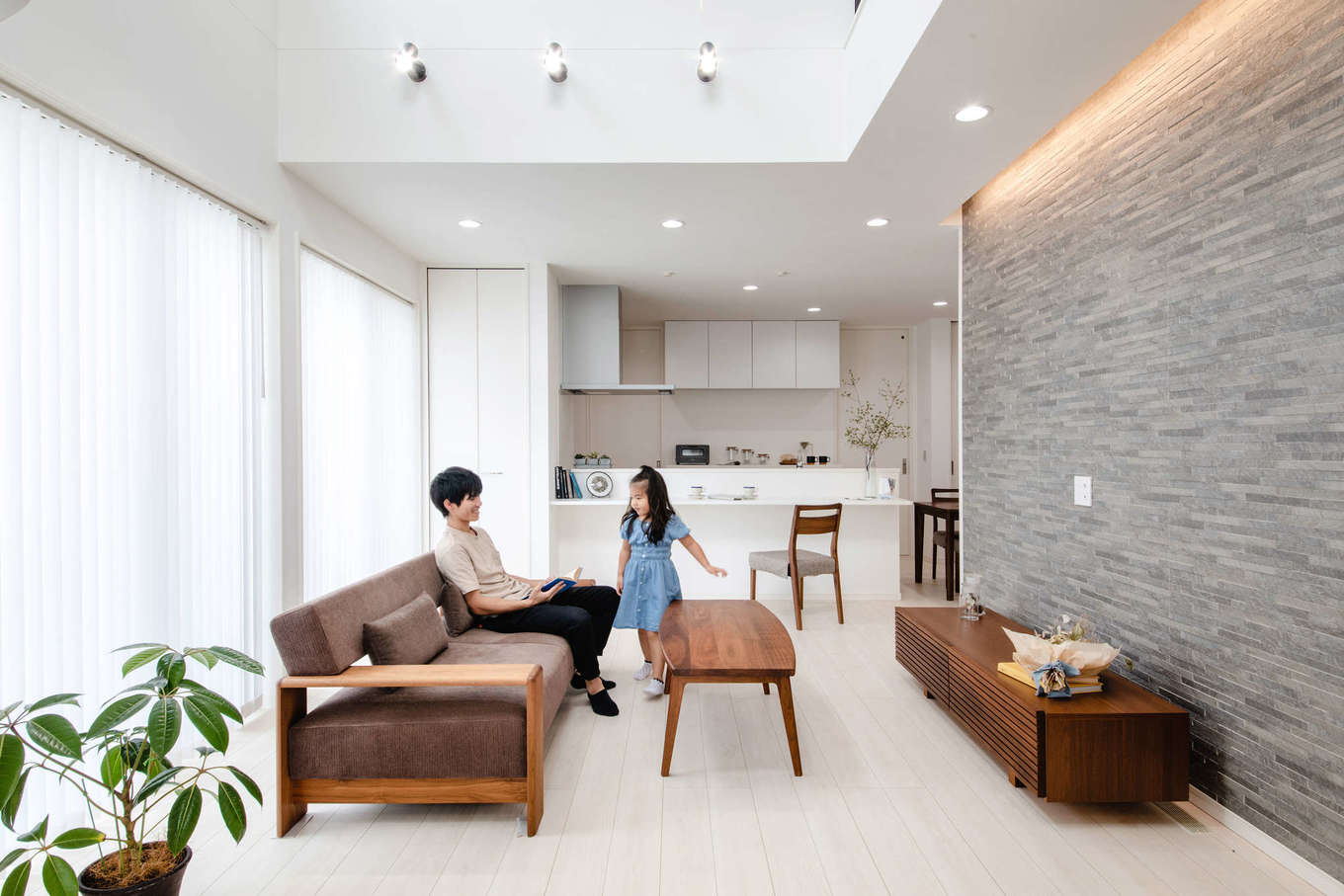 子育て安心住宅＆デザインラボ【デザイン住宅、子育て、間取り】吹き抜けのリビング。白を基調とした明るく清々しい空間が家族の団らんのステージ。石の素材感を活かしたアクセントウォールには間接照明を仕込んで上質感がアップ