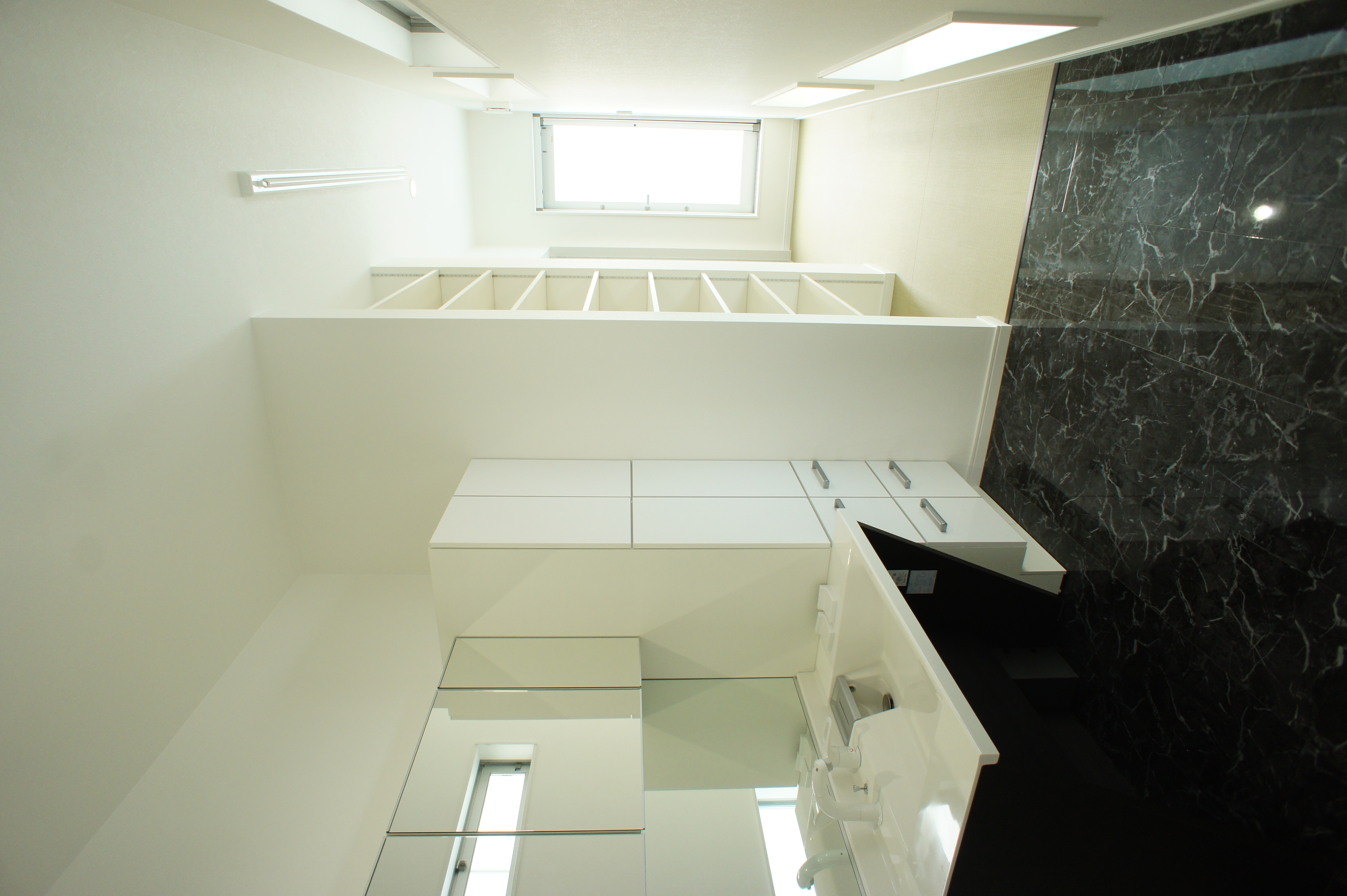 小野田産業～designers house project～｜明るく広々とした洗面スペースで、モダンなデザインが特徴的。大きな鏡と収納があり、朝の支度が快適にできる工夫がされている。