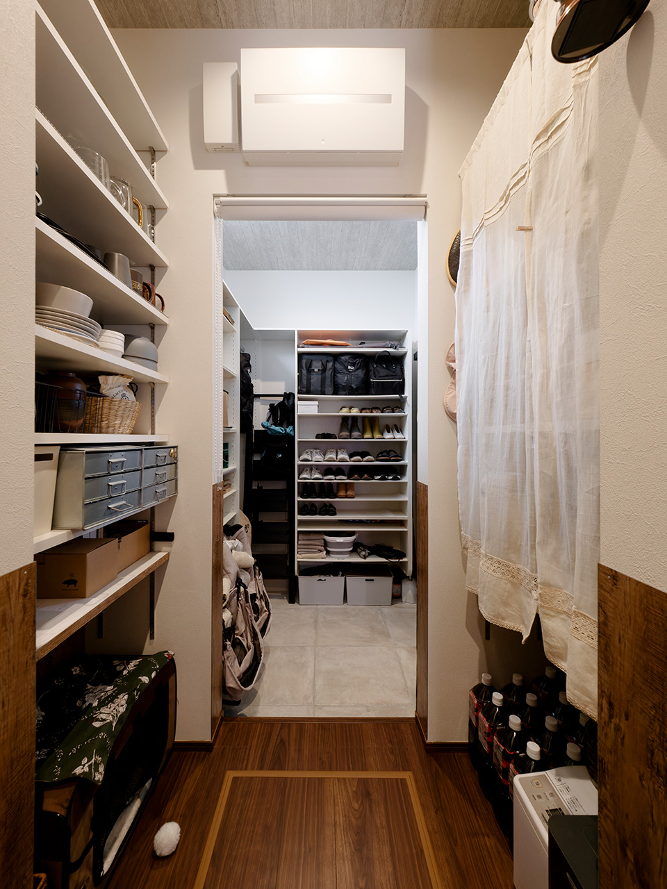 アサヒグローバルホーム｜キッチン～パントリー～土間収納を一直線にレイアウトした家事が楽になる魔法の動線。キッチンから生活感を排除するため、普段使いの食器などはパントリー内に収納し、キッチン背面のオープンラックはインテリアを楽しむ感覚でスタイリングしている