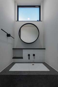 2階の洗面コーナー。丸鏡とタオル掛けは施主支給。高窓から光が差し込み、北面とは思えないほど安定した明るさを届けてくれる
