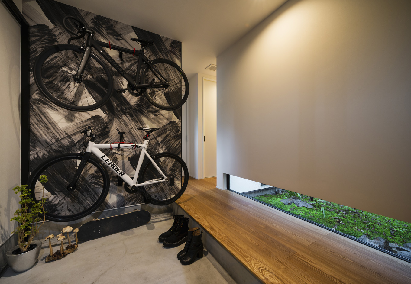S.CONNECT（エスコネクト）【趣味、夫婦で暮らす、平屋】自転車を壁掛けにした玄関。地窓の緑が白黒の空間に映える