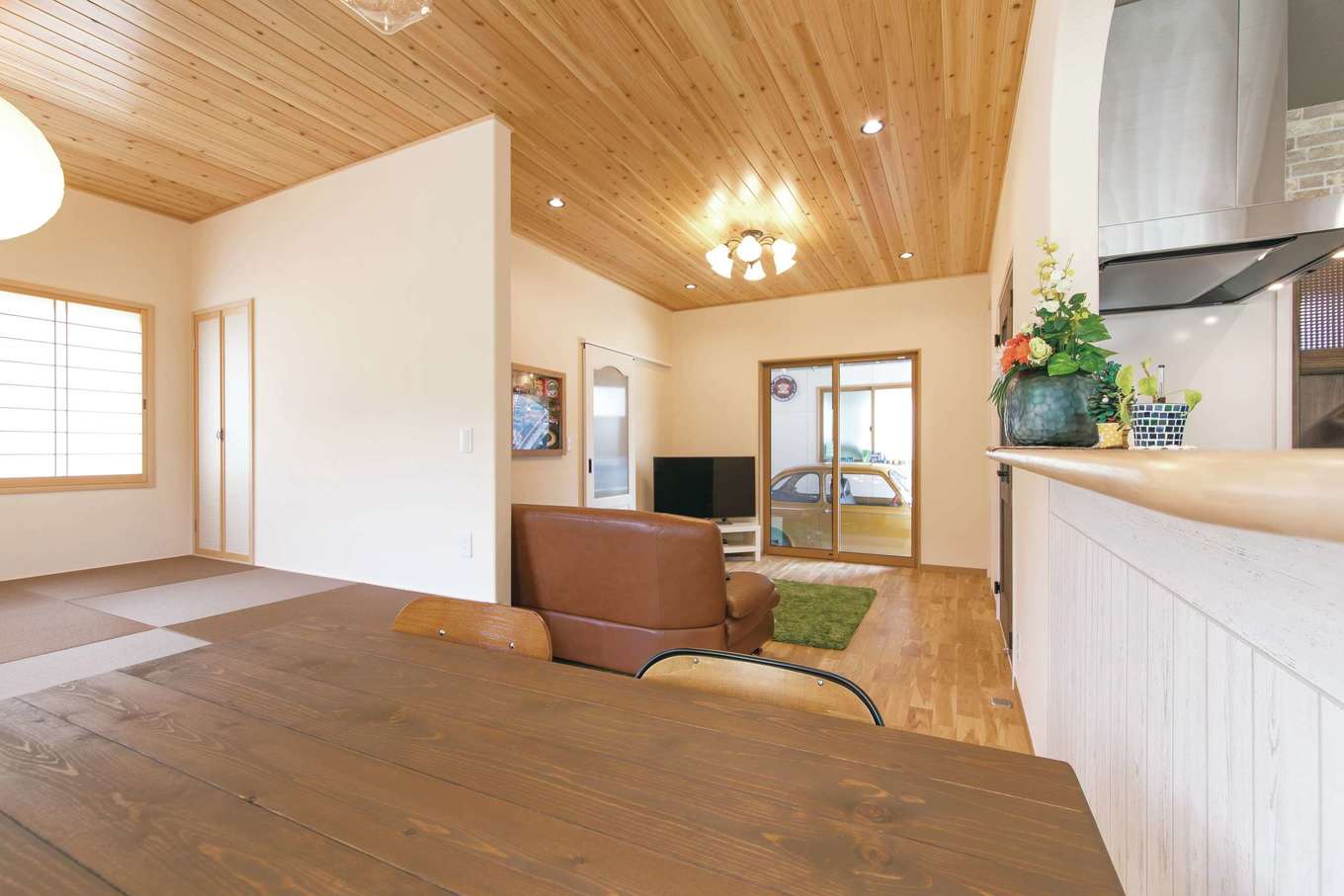 アキヤマ【自然素材、間取り、ガレージ】ダイニングからもガレージまで視線がのびる。小上がりの畳コーナーは、インテリアに合わせて茶色の畳をセレクト