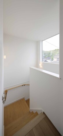 明るい自然光が差し込む階段。手すりが設置されており、安全性も確保されている。シンプルかつ洗練されたデザインで、空間に開放感を与えている。