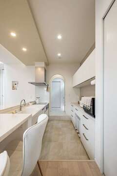 カウンター＆テーブルの高さに合わせるため、キッチンは一段下げダウンフロアとした。浴室まで動線が延び、家事効率をアップ。冷蔵庫は見えない位置に