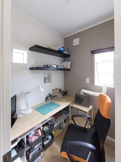 コンパクトで機能的なワークスペース。デスク周りには収納棚があり、文具や書籍の整理に便利。明るい窓から自然光が差し込み、作業に集中しやすい環境である。