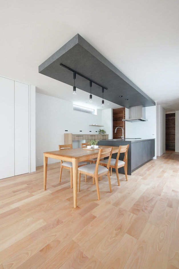 リビングと繋がる13帖のダイニングキッチン。キッチンの面材と色を合わせて備えた、奥行き4400mmの折り下げ天井が広々とした空間のアクセントに。