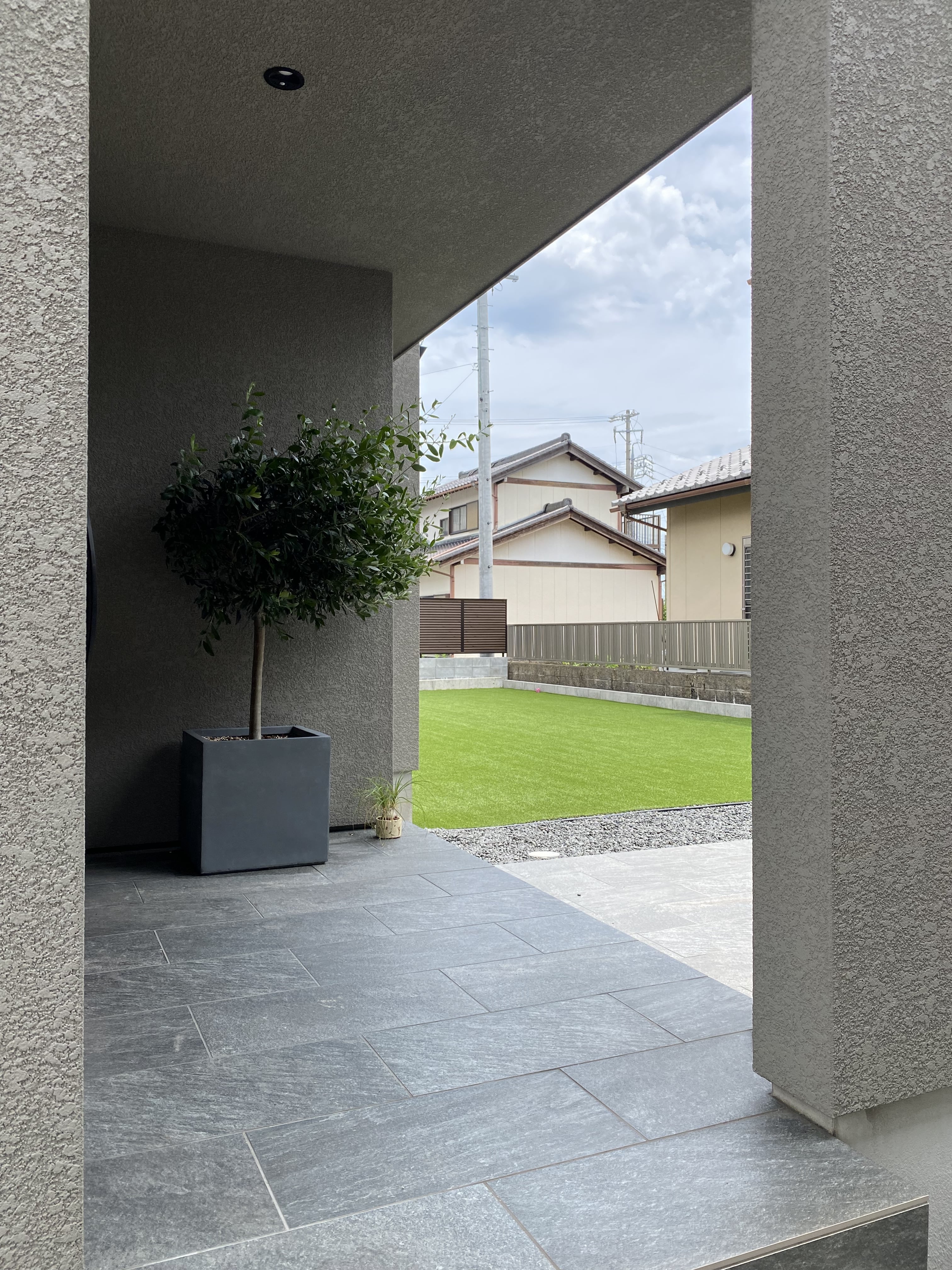 安田住宅｜安田建築設計室｜シンプルなデザインの玄関ポーチ。視線の抜け感を生かし、植栽がアクセントとなっている。屋外の庭につながる開放感が特徴。