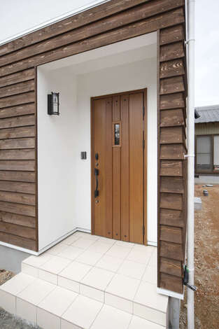 鎧張りの外壁の素材感が個性を放ち、コンパクトでありながらインパクトのある玄関ポーチ