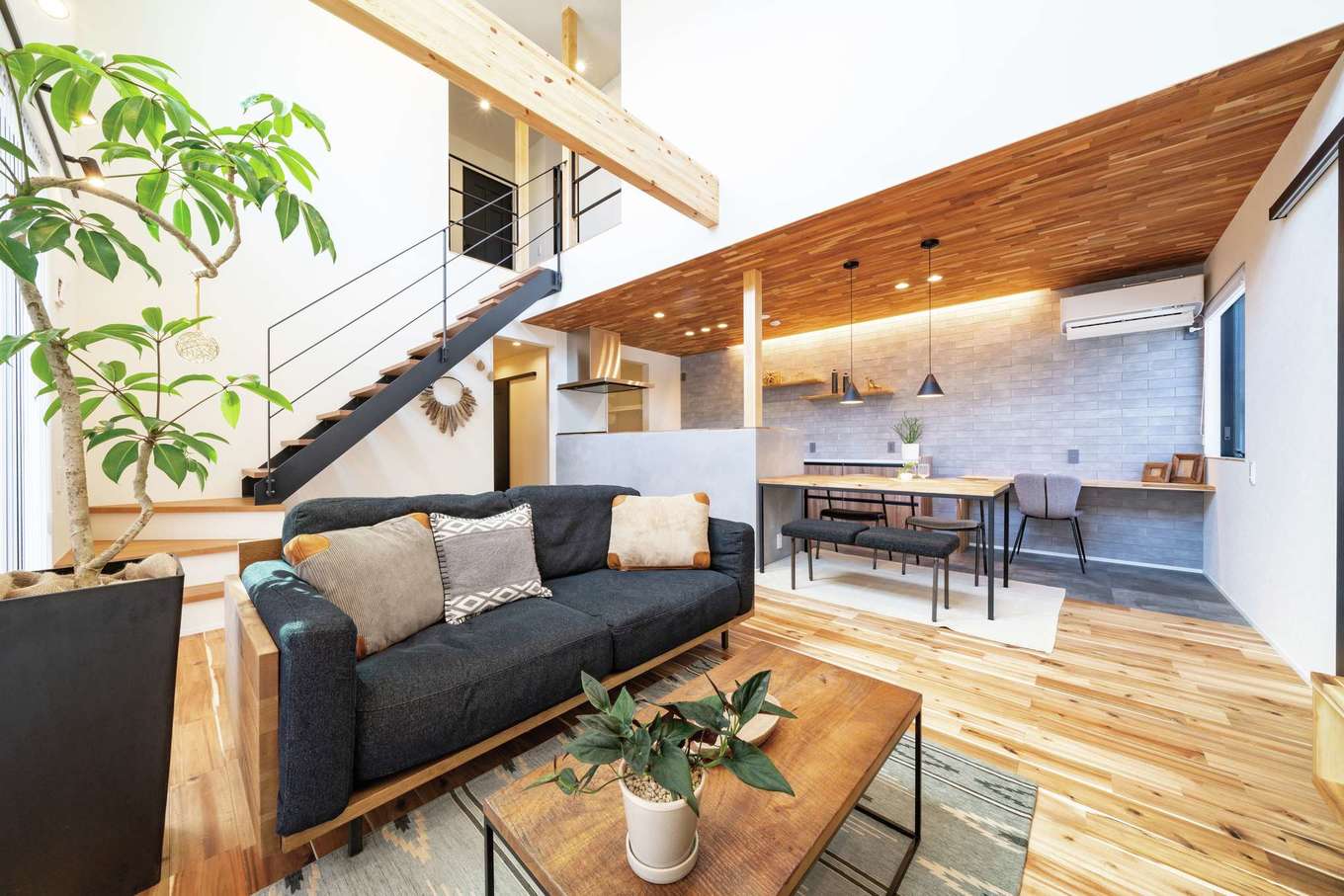 住家 JYUKA【デザイン住宅、ペット、建築家】グレー・黒・木目でコーディネートしたカフェスタイルのLDK。無垢材、タイル、アイアンといった素材ミックスがあたたかくて心地いい空間を演出する。ダイナミックな吹抜けのリビングの大きな高窓からやわらかな光が射し込み、朝から夕方遅い時間まで照明がいらない。アカシアの床の経年変化も楽しみ
