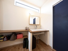 シンプルで機能的な洗面スペース。ナチュラルな木目調のカウンターと壁掛けの鏡が、清潔感を演出している。