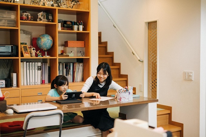 階段の途中につくられたスタディスペース。子どもと一緒に宿題ができるデスクが配置され、背面の本棚には教材や趣味のプラモデル等が並ぶ。スキップフロアとなっており、座っていても家族と目線が合う工夫がされている。