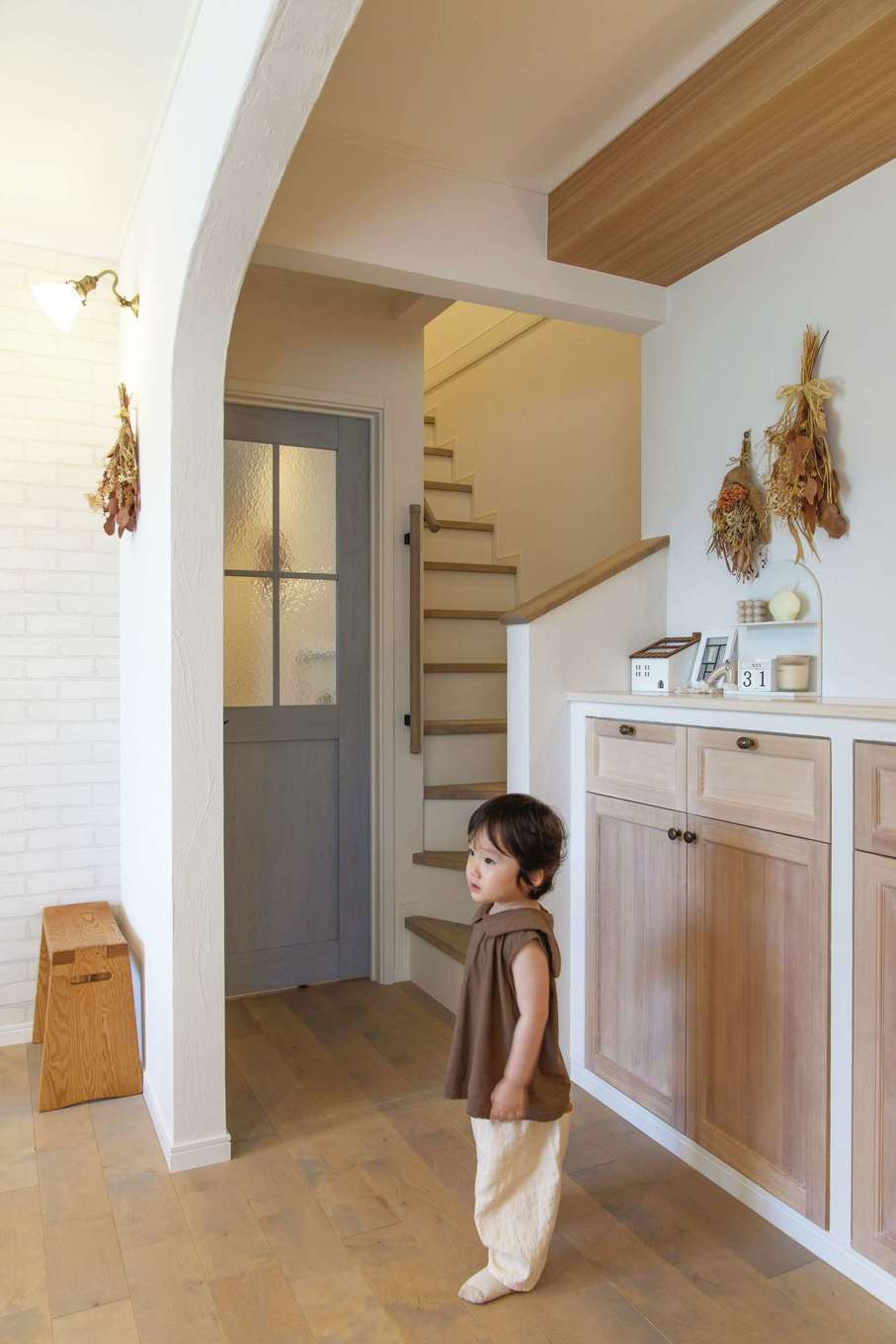 ハートホーム【デザイン住宅、自然素材、間取り】リビングドアはさわやかなブルーでアクセント。階段は必ずリビングを通ることを意識してこの位置に。造作収納の扉は框のあるデザインにこだわった