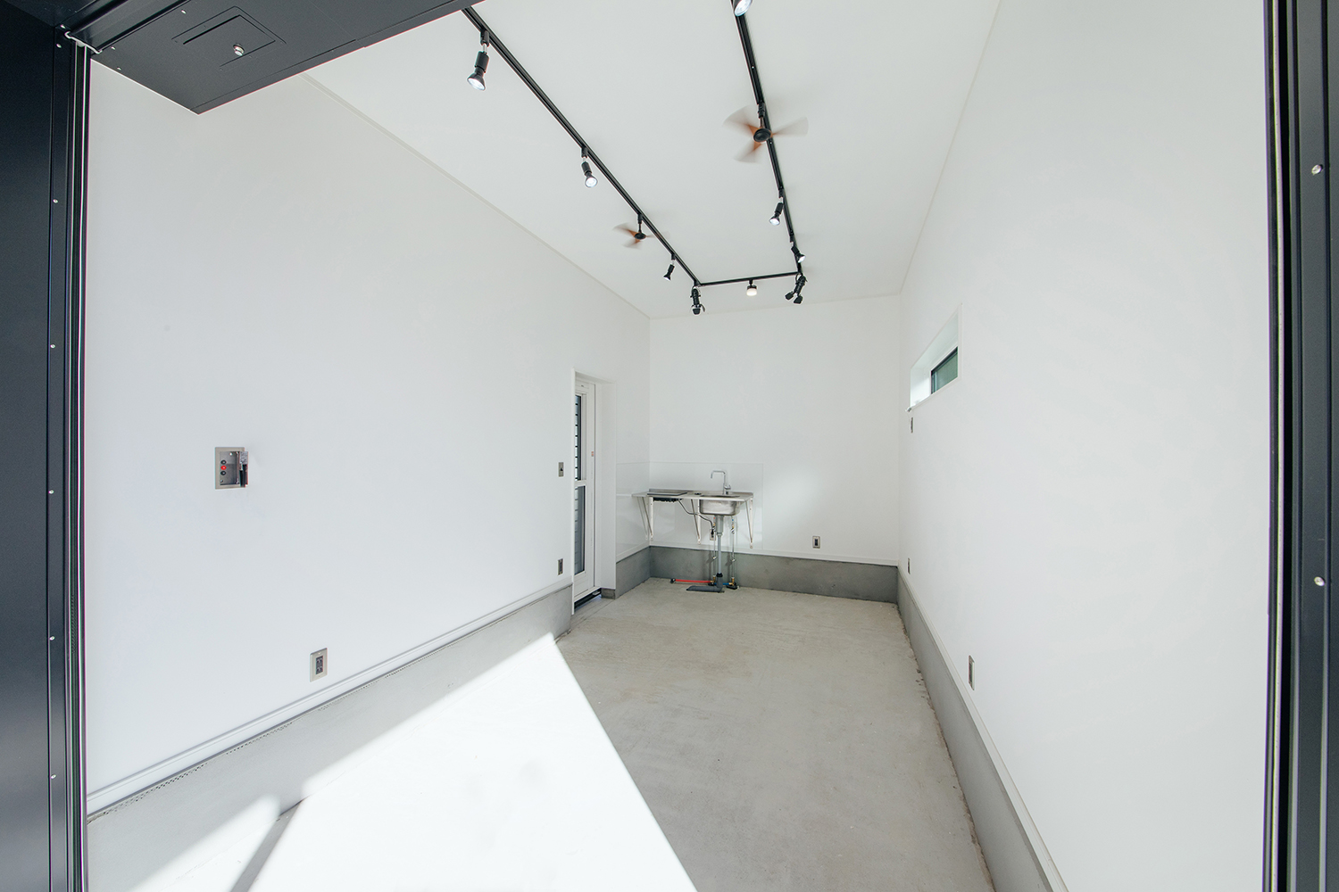 LIXIL住宅研究所 フィアスホーム【デザイン住宅、省エネ、間取り】白い壁と天井で清潔感あるインナーガレージ。シンプルさが際立つデザインと便利な洗面台が設置されている