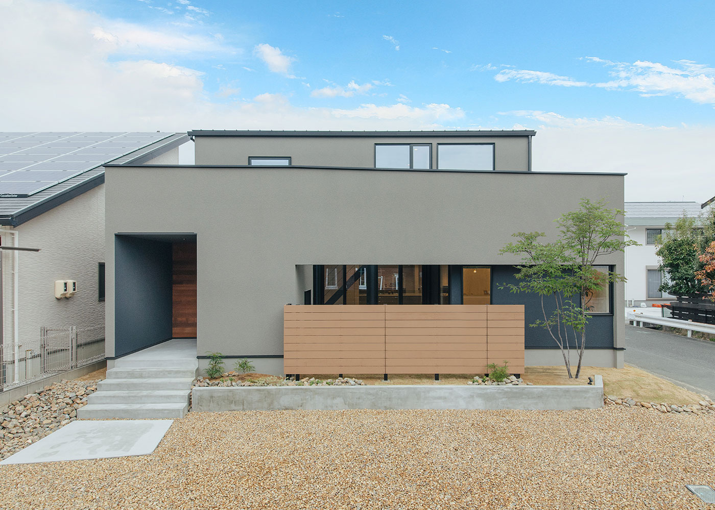 S.CONNECT（エスコネクト）【子育て、間取り、建築家】敷地は東南に道路のある住宅街。高低差のある敷地を利用して、道路面と1階床高さには90cmほど差が出るようにプランニング。こうすることで、道を歩く人から家の中が見えにくくなっている。外壁素材はグレージュとブラックのジョリパット