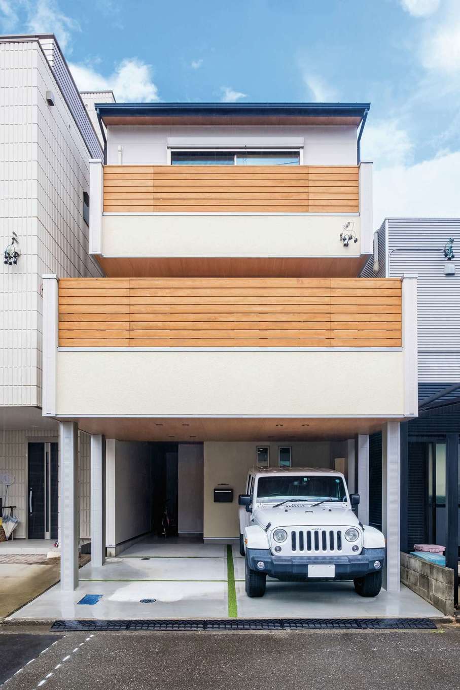 靖和工務店【子育て、狭小住宅、間取り】バルコニーの木製フェンスがナチュラルな印象の外観。張り出したバルコニーの支柱は、安心の鉄骨製で、駐車場2台分を確保。玄関脇には便利なサイクルポートを完備