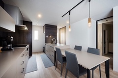 グレージュのキッチンにダークカラーのアクセントパネルが調和したダイニング。