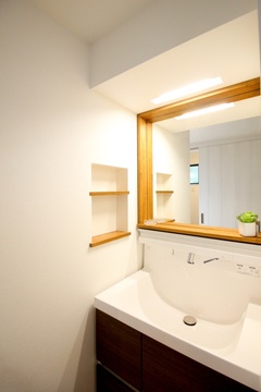 シンプルで機能的な洗面スペース。清潔感のあるデザインが特徴で、木枠のミラーがナチュラルなアクセントとなっている。