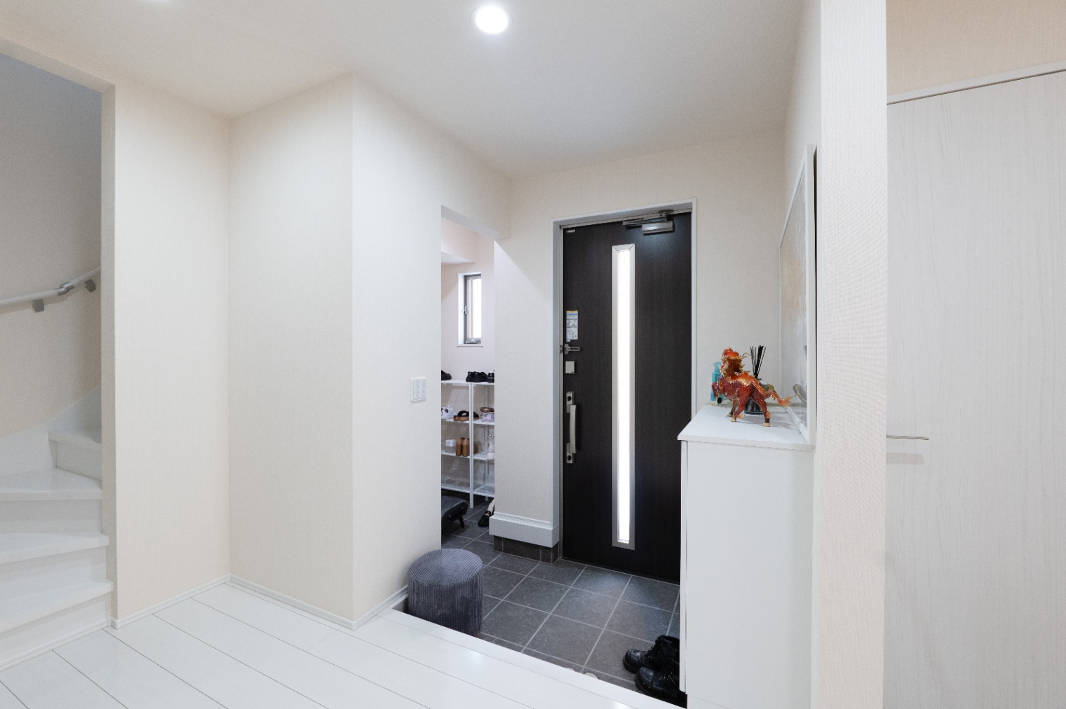 アイダ設計　｜シンプルでモダンな玄関スペース。明るい色調の床と対照的な黒いドアが印象的なエントランス。
