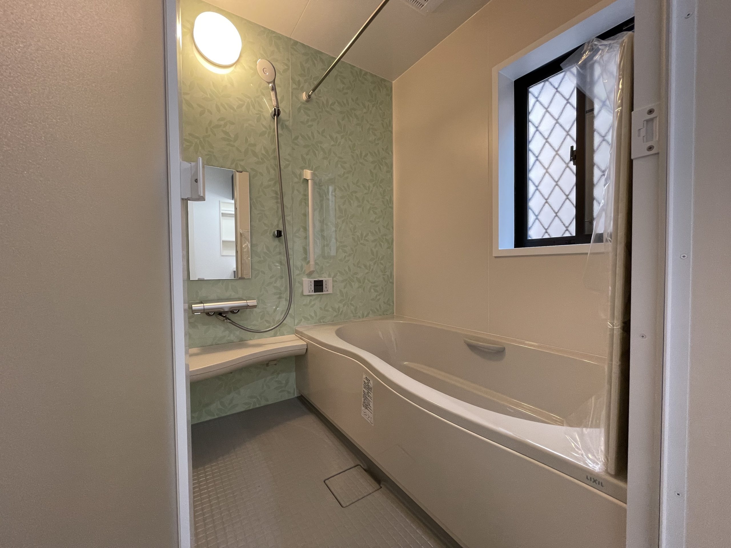 タムラ建築設計｜シンプルで機能的なバスルーム。広々とした浴槽と使いやすいシャワーがリラックス空間を演出。大きな窓が自然光を取り込み、心地よい明るさを提供している。