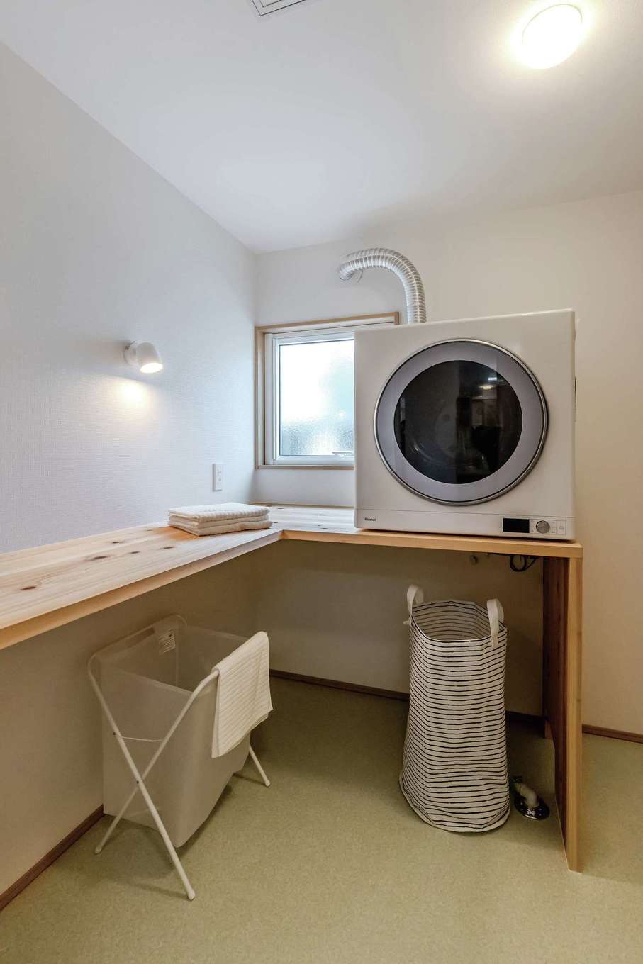 住まいるコーポレーション【自然素材、省エネ、夫婦で暮らす】ゆったり広々のランドリールーム兼脱衣室。L字の造作カウンターはアイロンをかけたり、洗濯物をたたんだり使い勝手も抜群。ガス衣類乾燥機は共働き・子育夫婦になくてはならない強力な助っ人だ