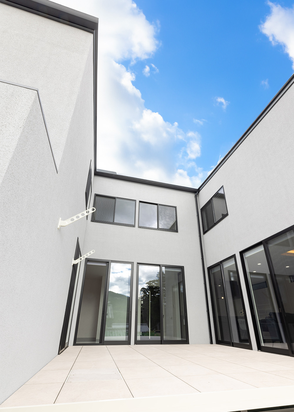 ARCHITECT STUDIO TEGOKORO （遠藤建築店）【デザイン住宅、間取り、インテリア】中庭のデッキの高さはリビングの床の高さに揃えて設計。玄関を開けたらそのまま中庭まで地続きに見えるようになり、開放感がさらにプラスされた