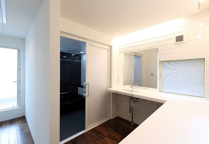 丸昇彦坂建設【デザイン住宅、間取り、ガレージ】2階の洗面コーナーはカウンターをL字型に配置してあるので、アイロンがけや洗濯物をたたむのにも便利。左手奥がバルコニーになっていて動線も考慮