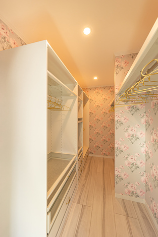 花柄の壁紙が印象的なウォークインクローゼット。効率的な収納配置で、衣類や小物を整然と保管できる空間になっている。