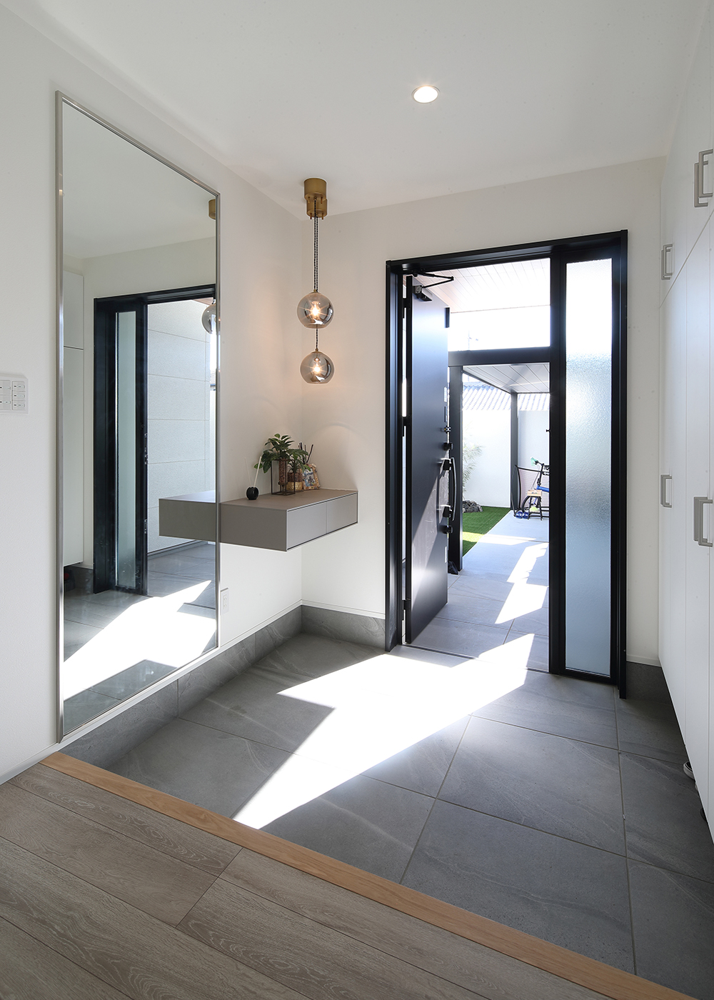 TOZAKI HOME 戸﨑建設　【デザイン住宅、間取り、インテリア】大きな鏡と浮遊感のある飾り棚が印象的な玄関。提携している家具ショップがインテリアのコーディネートを担当