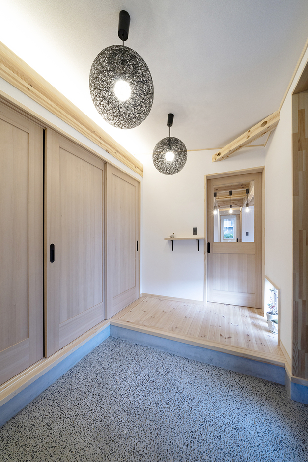 シンプルで広々とした玄関土間。和モダンな照明が空間を引き立て、清潔感のあるデザインを提供している