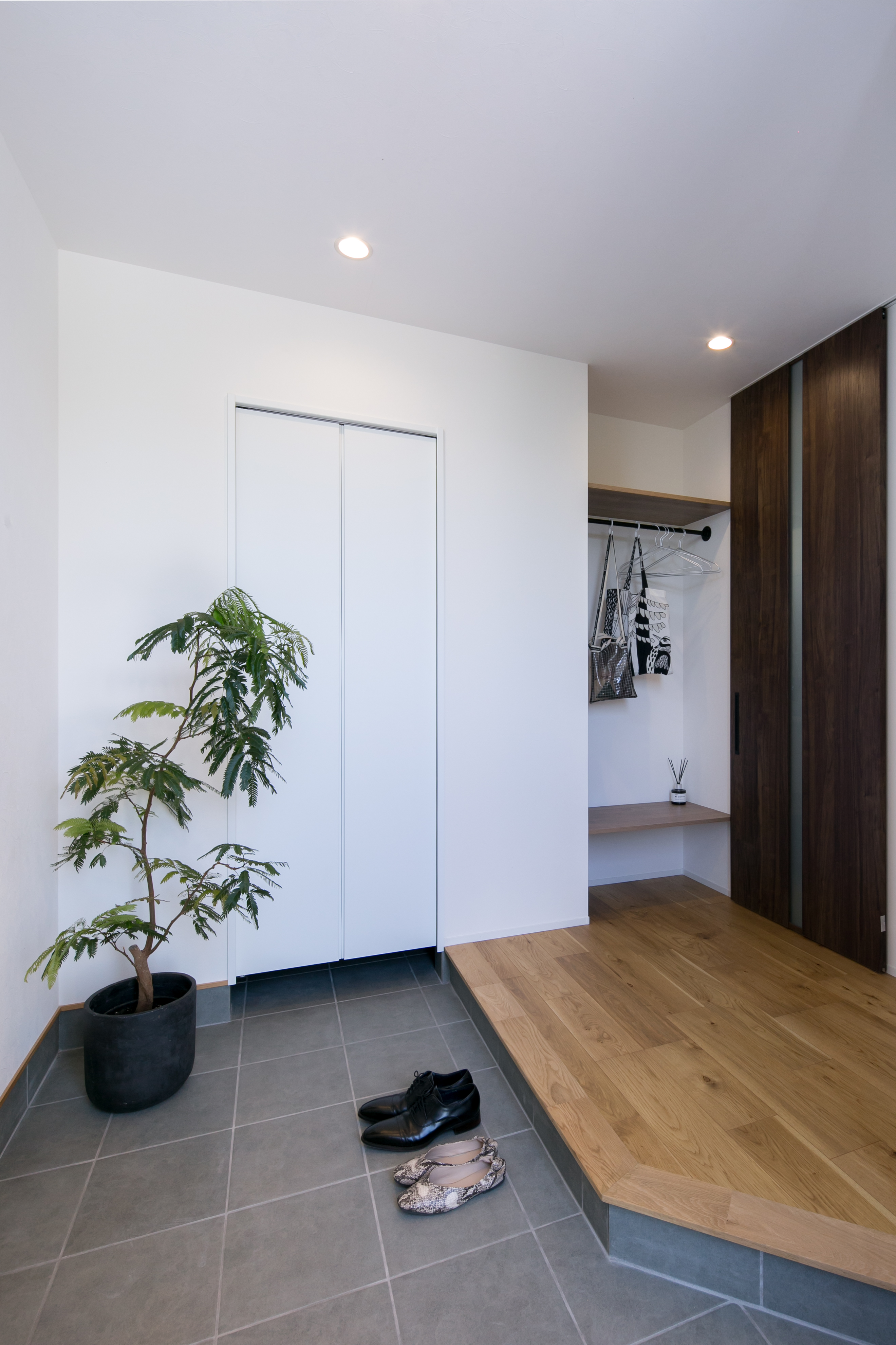 シンプル｜広々とした玄関。
奥の扉を開けるとSCL、その横にはコートやカバンを置けるようアイアンと棚を設置。