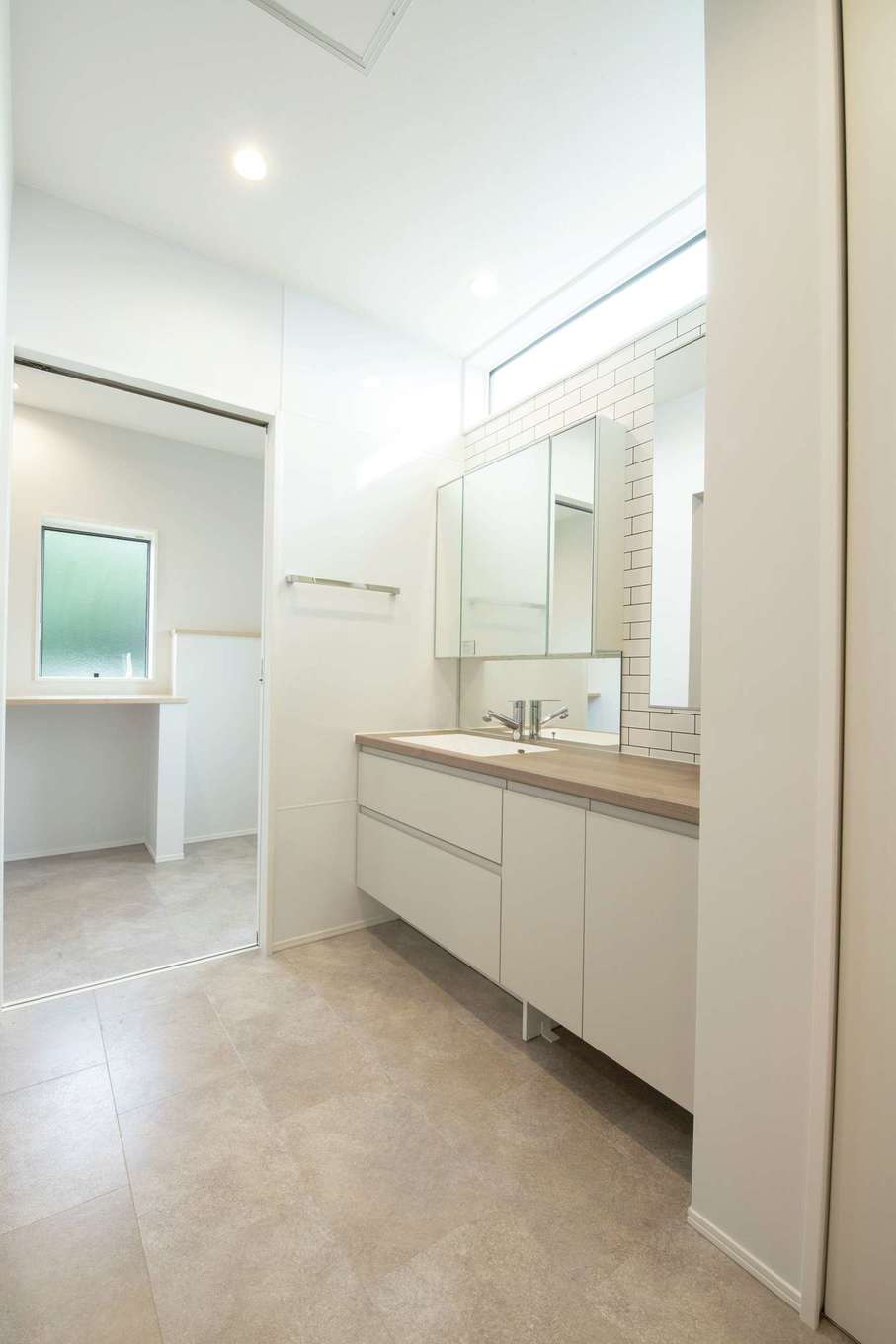 遠州鉄道 遠鉄ホーム【デザイン住宅、狭小住宅、インテリア】ホテルのパウダールームのような洗面所。奥には脱衣室があり、室内干し空間としても活用できる。来客があっても、脱衣所の扉を閉めるだけで洗濯物を隠せるから便利。洗面の向かいにはファミリークローゼットを用意