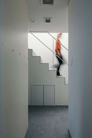 オブジェのように美しいデザイン階段。緊張感のあるアイアンの細い手すりがおしゃれ。階段下は収納スペース