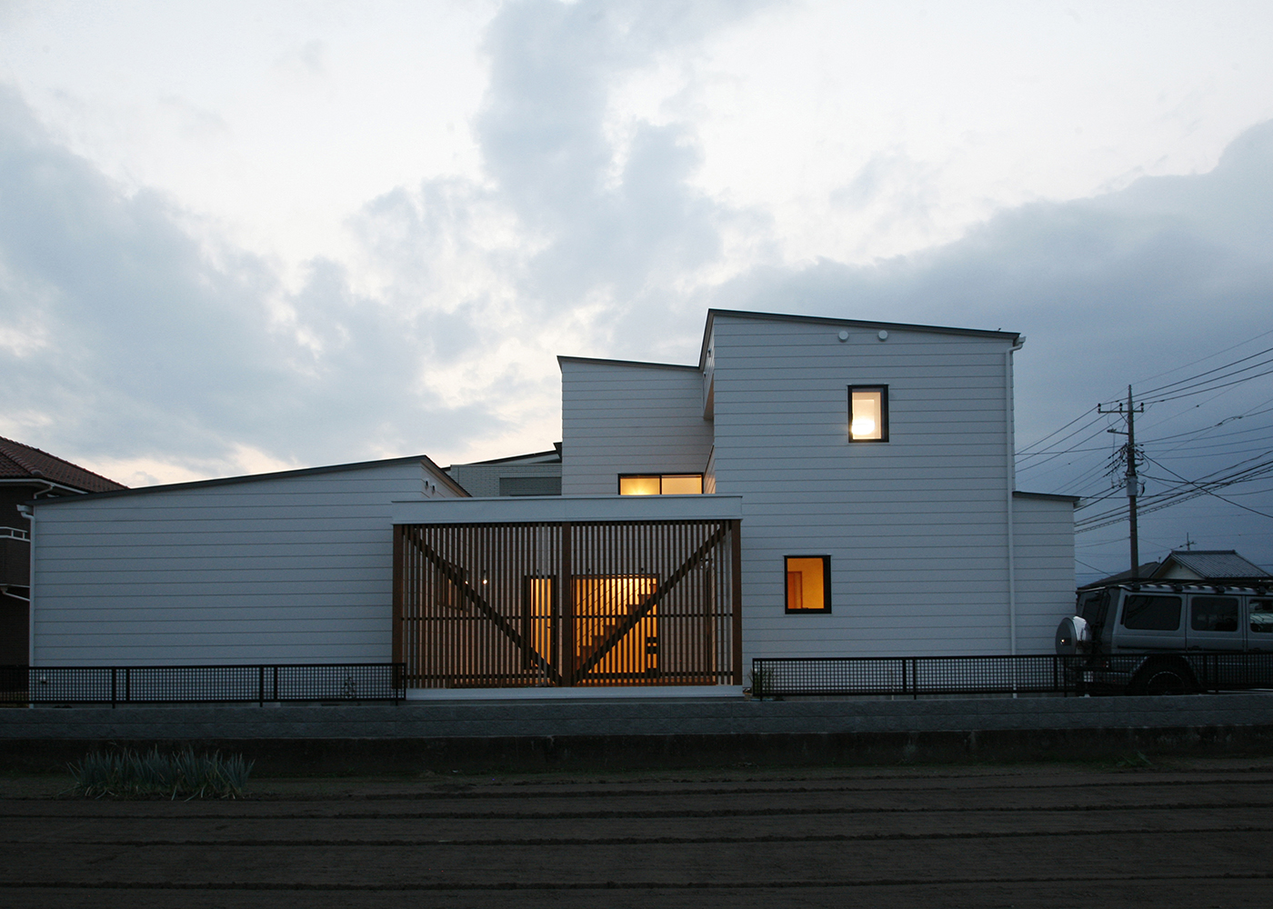 タツホーム・竜建｜モダンなデザインのファサードが印象的な住宅の外観。夕暮れに映える造形が、家のシンプルな美しさを引き立てる。