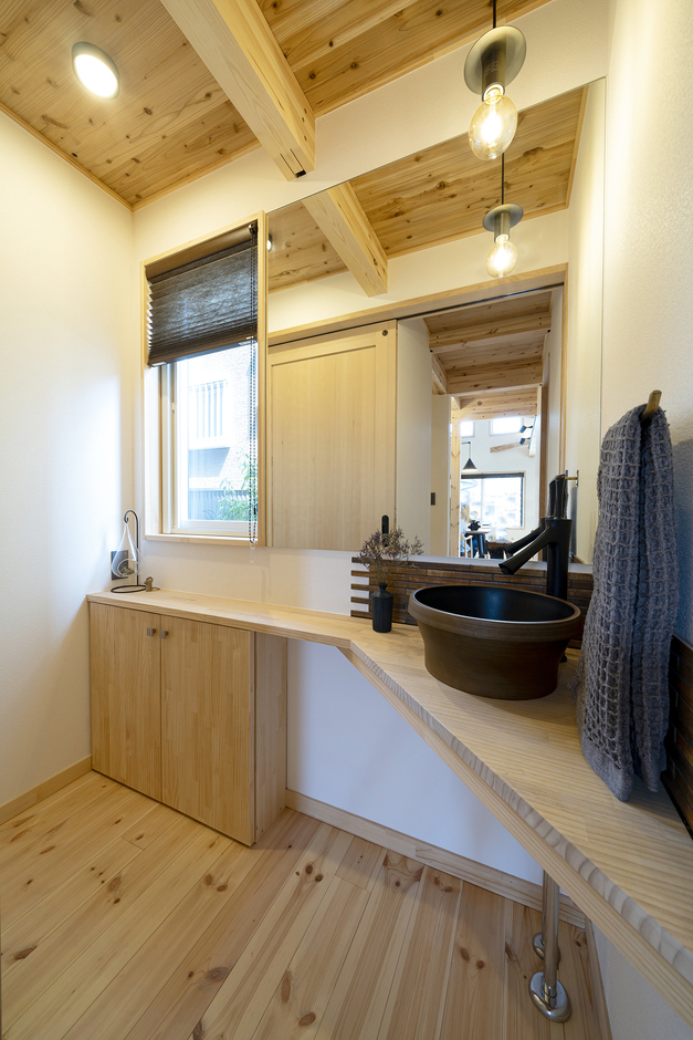 ナチュラルな木目が美しいトイレの洗面スペース。明るい照明が備わり、シンプルで使い勝手の良いデザインが施されている。