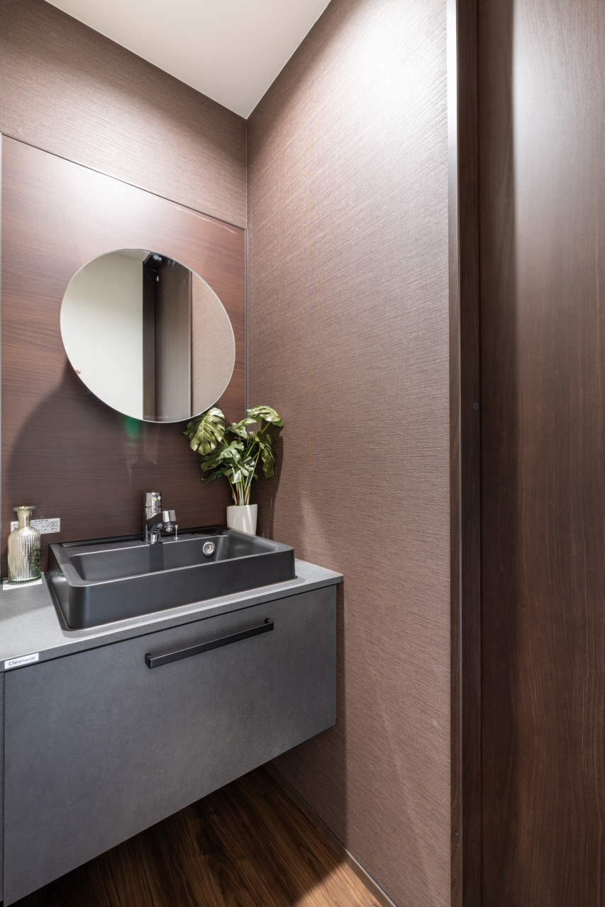 サンジョーホーム｜モダンでスタイリッシュな洗面スペース。シンプルなデザインながら、高級感が漂う。丸い鏡と洗練されたシンクが、空間にアクセントを加えている。