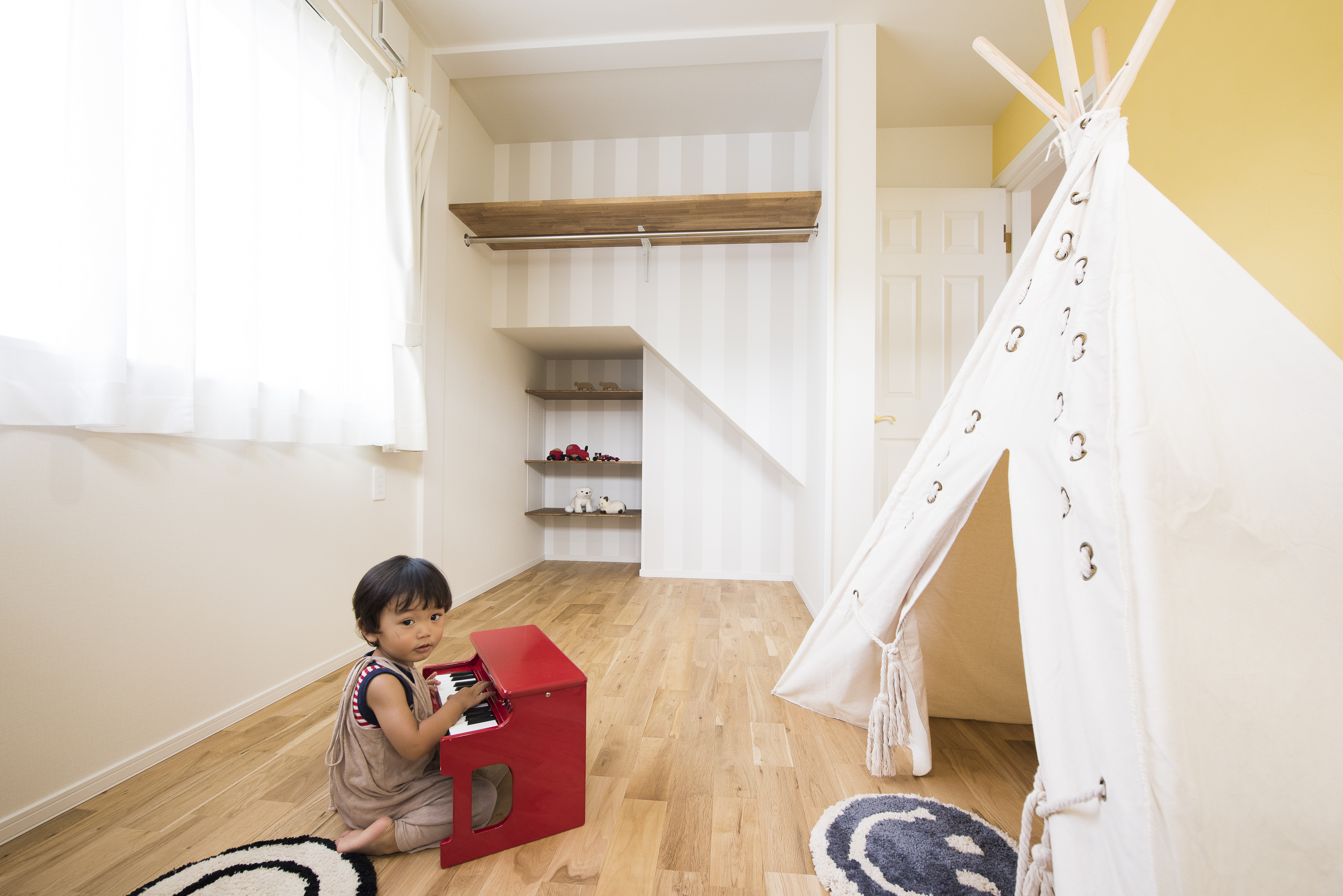 F.Bird HOUSE（袴田工務店）【子育て、間取り、ガレージ】一面をレモンイエローの塗り壁にした子ども部屋。クローゼット内側のストライプ柄がアクセント