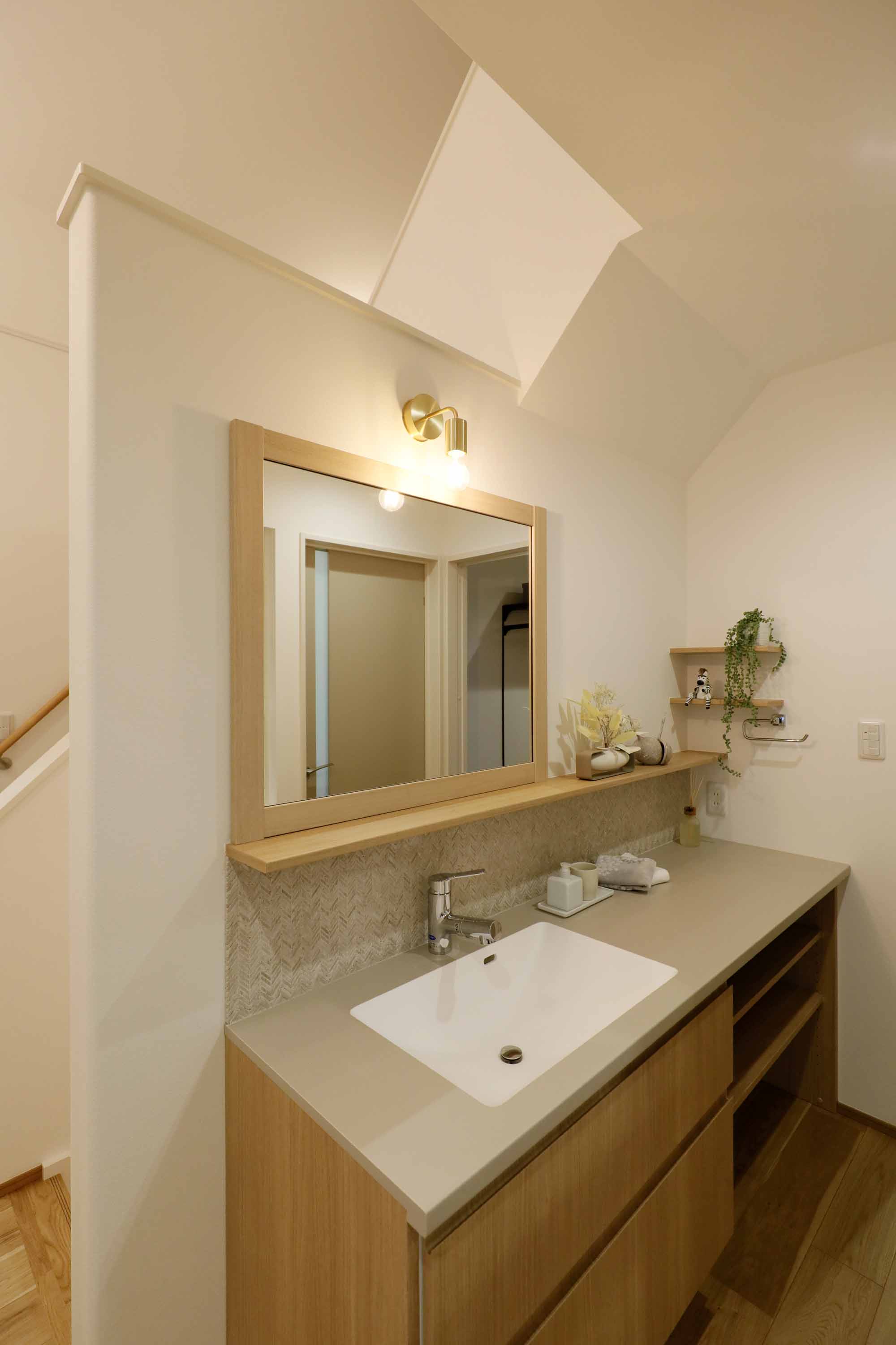 サーラ住宅 名古屋支店｜明るい照明が設置された洗面スペース。広々としたシンクと棚が使い勝手を高め、シンプルで機能的なデザインが特徴的である。