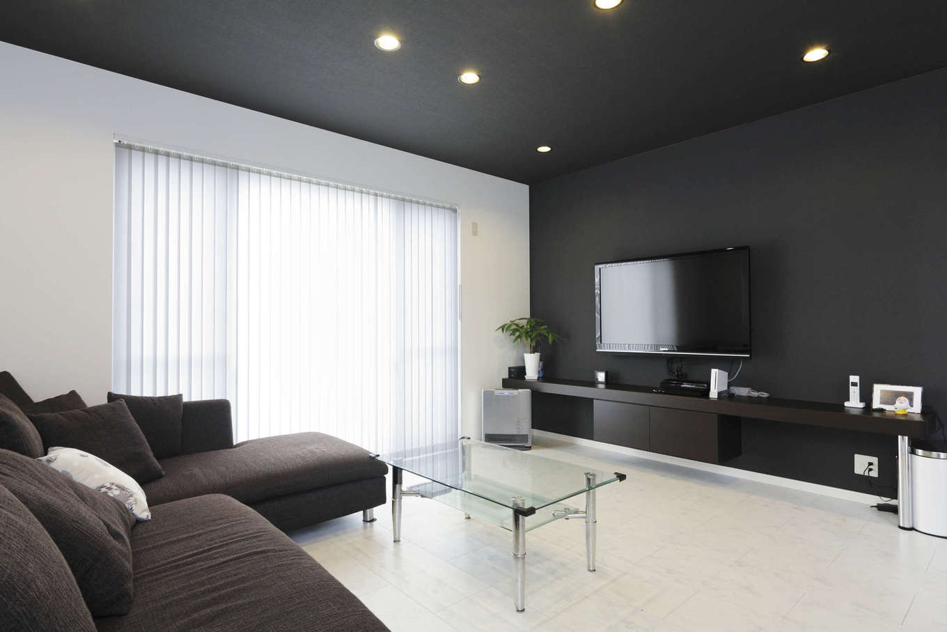 吉川住建【1000万円台、デザイン住宅、建築家】「バーのようなデザインに」と、リビングの天井や壁は黒を基調としたシックな雰囲気に。壁一面のテレビボードは造り付けで、おしゃれなデザインに仕上がっている。黒い天井に埋め込まれたダウンライトも、よりアーティスティックな雰囲気を演出している