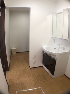 シンプルで清潔感のある洗面スペース。収納付きの洗面台が使い勝手を向上させる。床は温かみのある色合いで統一されている。