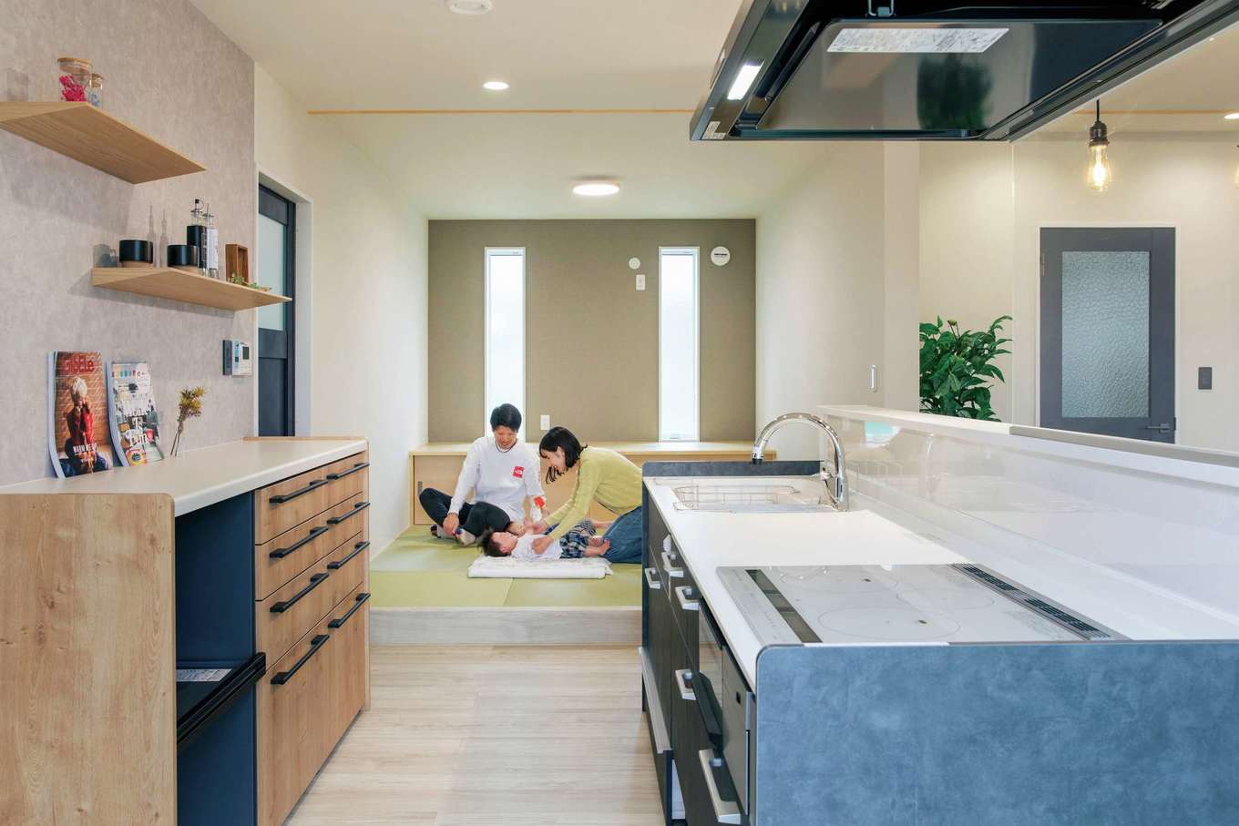 桜建築デザイン【デザイン住宅、子育て、間取り】キッチン横の小上がりの床下は引き出し収納になっていて、子ども用の布団などをしまっておける。上り下りのしやすさを考えて、高さはあえて低めに設定