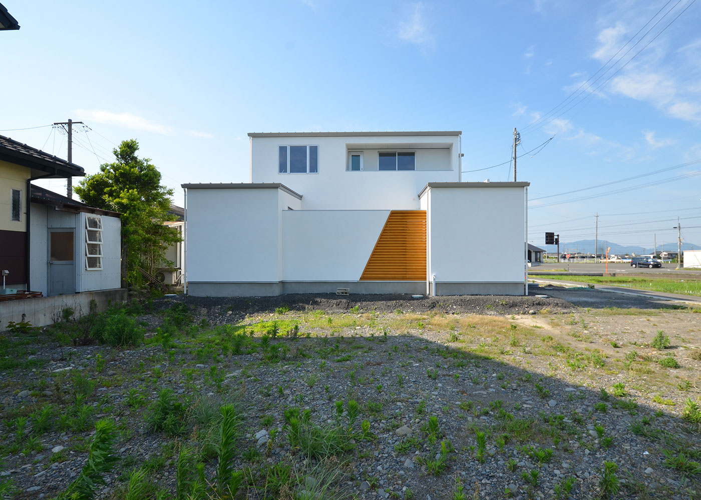 Touch House（タッチハウス）【デザイン住宅、夫婦で暮らす、間取り】白い外壁にモダンな桧の格子をアクセントに。格子の内側には中庭が配置され、心地よい風が入ってくる。外壁を斜めに切り取るデザインが住まいの個性となっている